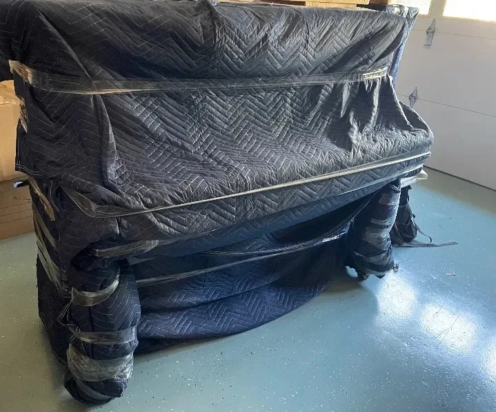 Upright piano, double-blanketed in the garage